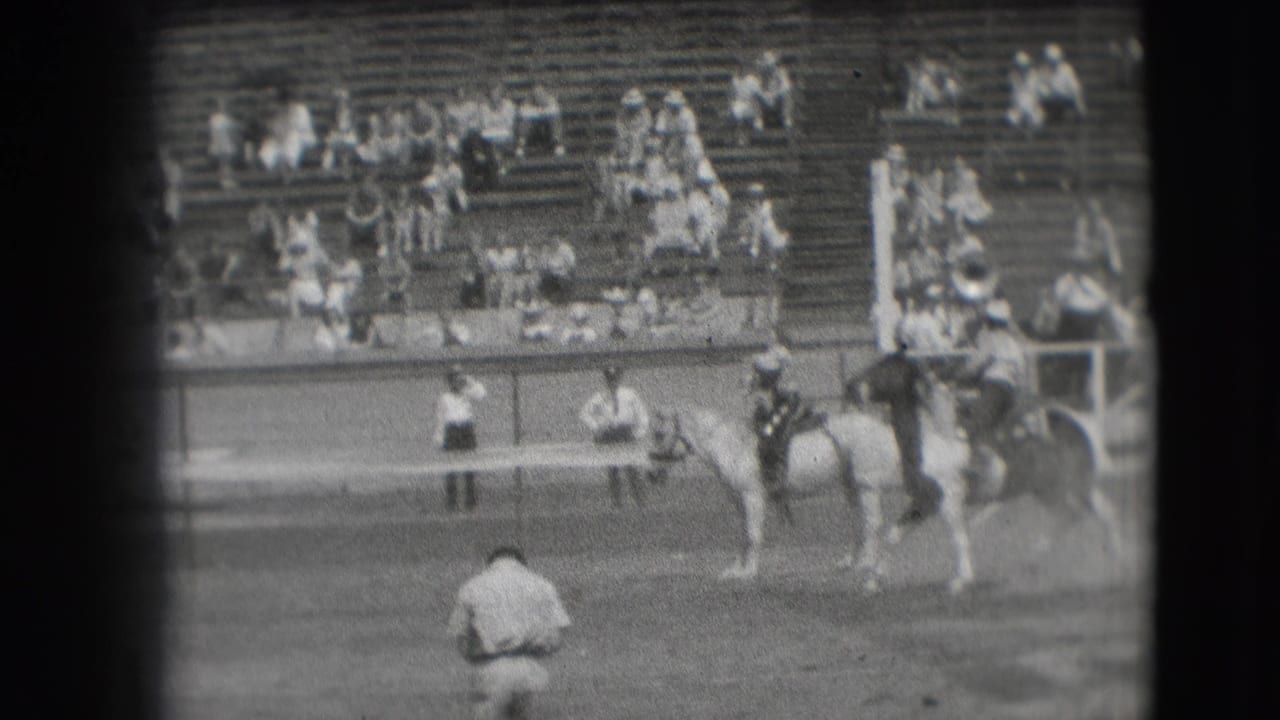 1941 Denver rodeo frame showing mounted riders in the dirt arena with spectators spread across wooden bleachers.
