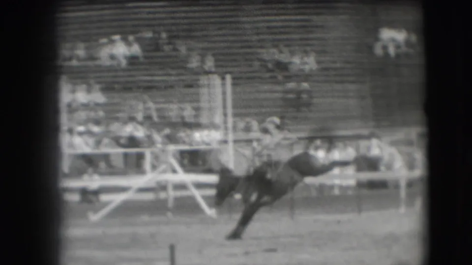1941 Denver rodeo frame showing a bucking horse as a rider appears to be thrown near the arena rail.