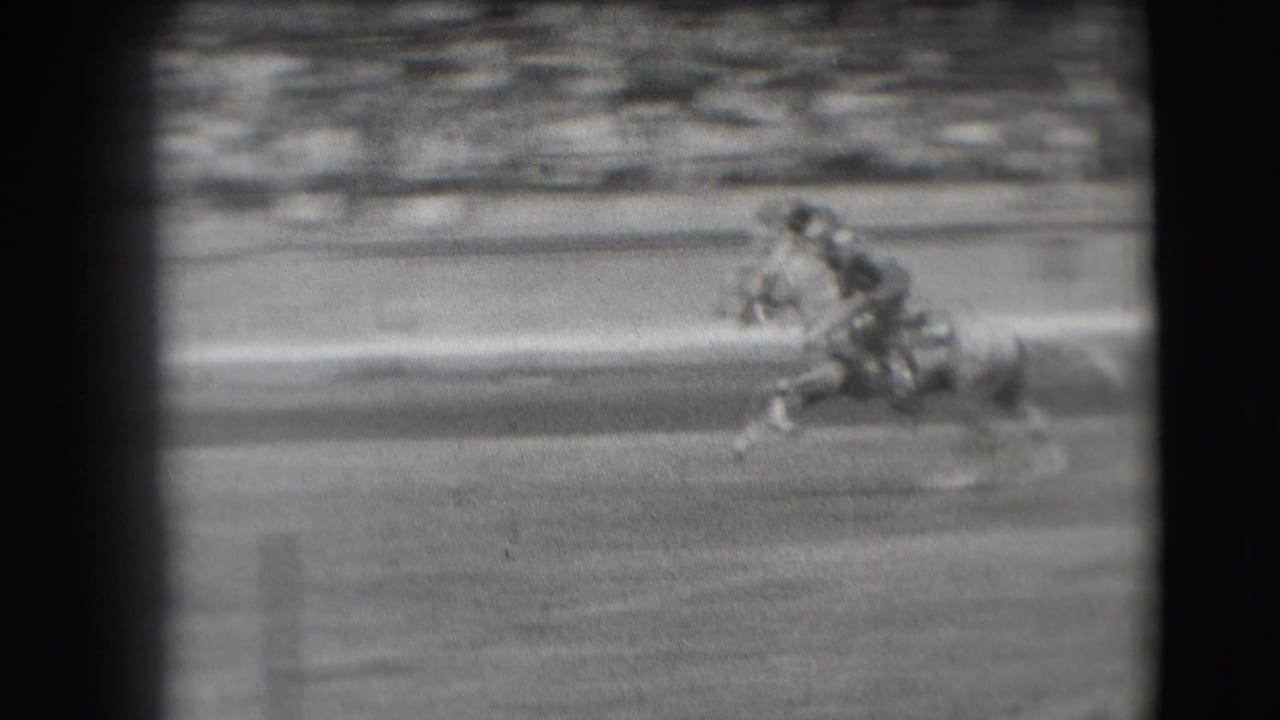 Near the end of the clip, the rider is low against the moving horse as the Denver rodeo arena and bleacher crowd blur in the background.