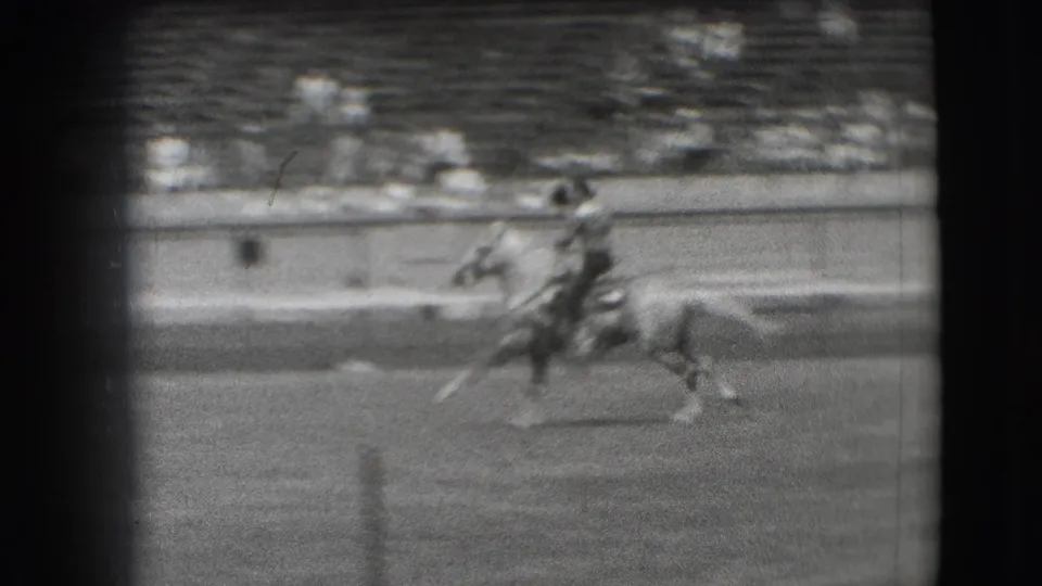 1941 Denver rodeo footage showing a rider on horseback crossing the arena in front of tiered spectator seating.