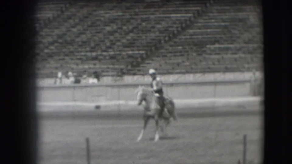 In 1941 Denver footage, a cowboy-style rider on a light horse moves across an open stadium arena with bleachers behind.