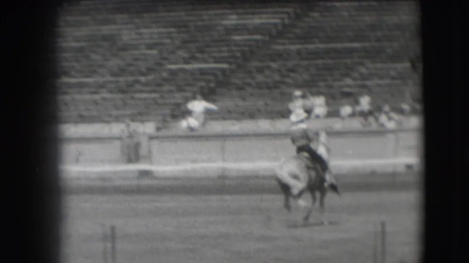 A cowboy-style rider on horseback is seen near the stadium rail, with soft focus and motion blur from the 8mm home-movie scan.