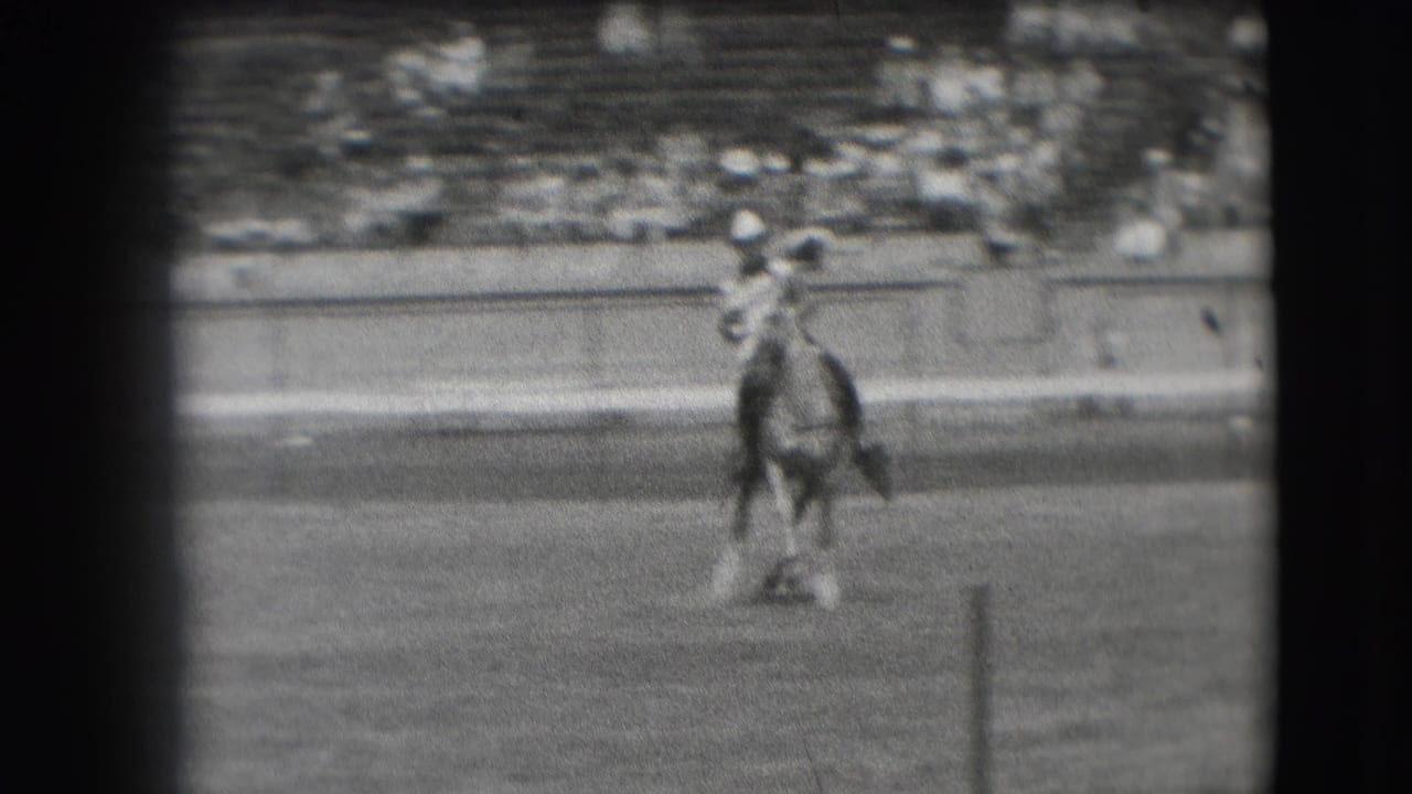 A horse and cowboy-hatted rider face the camera in the 1941 Denver arena, framed by grain and dark edges.