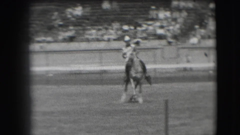 A horse and cowboy-hatted rider face the camera in the 1941 Denver arena, framed by grain and dark edges.