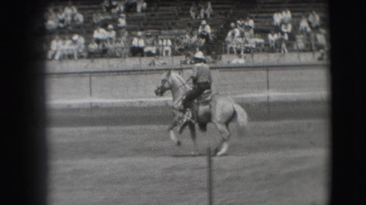 In the 1941 Denver home-movie clip, a rider guides a light-colored horse across an outdoor arena before seated spectators.
