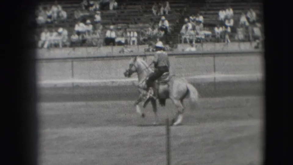 In the 1941 Denver home-movie clip, a rider guides a light-colored horse across an outdoor arena before seated spectators.