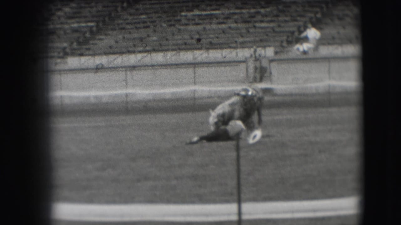 During the Denver horse-show footage, the light-colored horse bends low near a small post in the grassy arena as spectators remain in view.