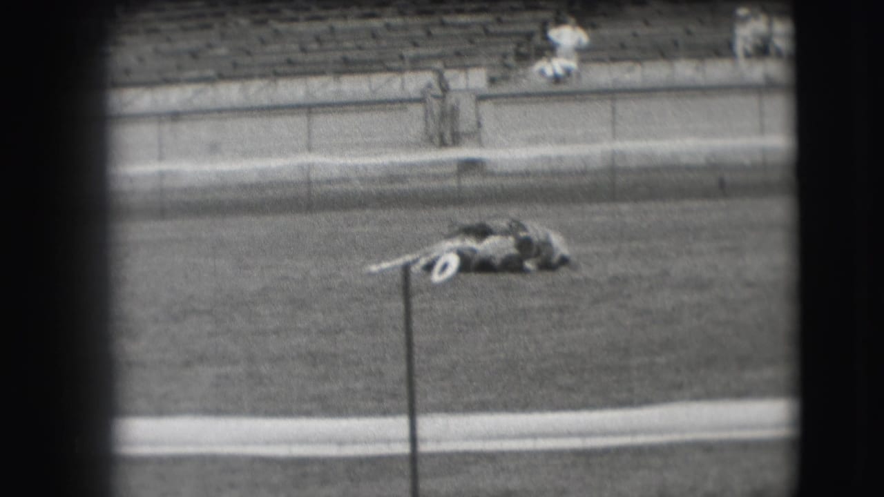 1941 Denver home-movie frame with a cowboy and horse still lying low in an arena, backed by mostly empty bleachers.