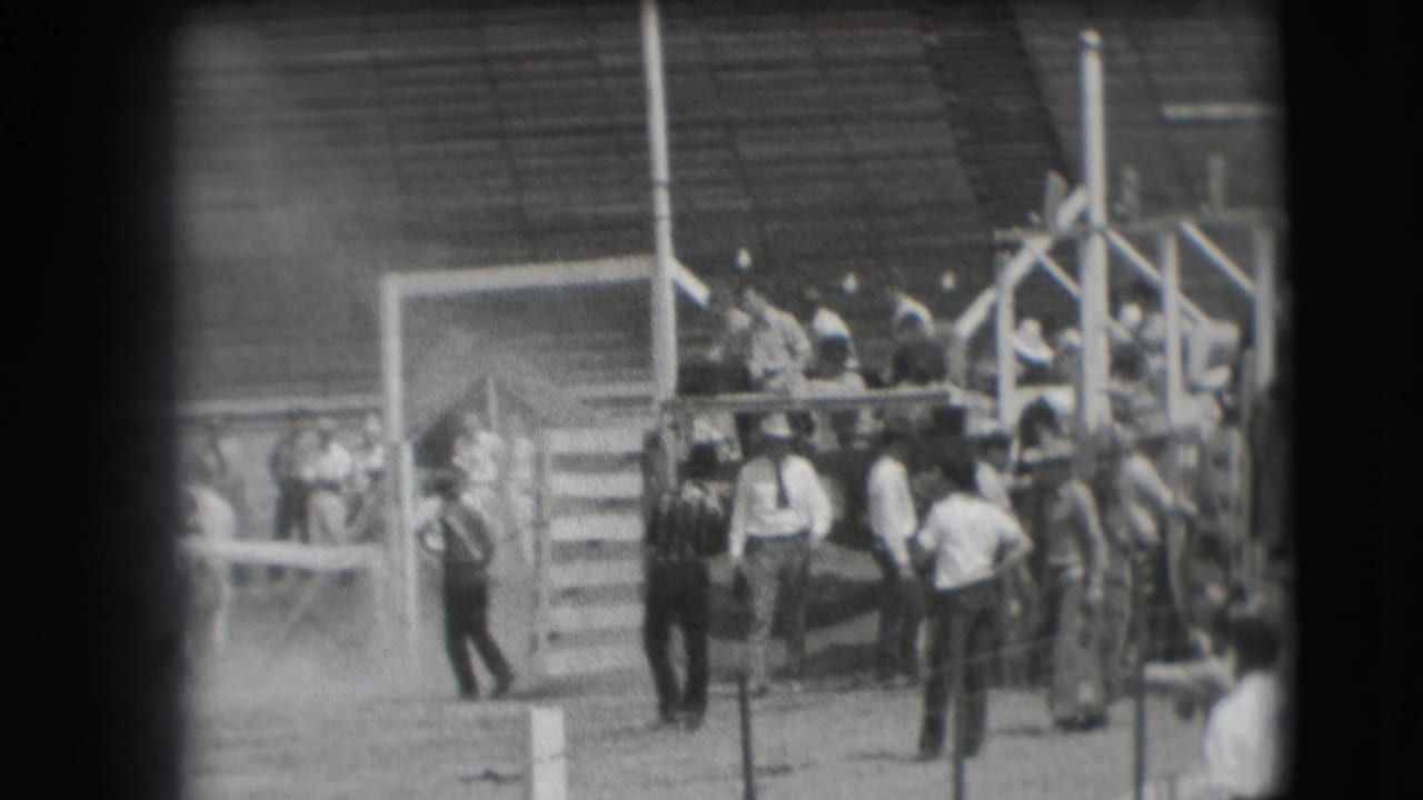 People cluster around the Denver rodeo chute area in 1941, with bleachers and arena structures behind them.