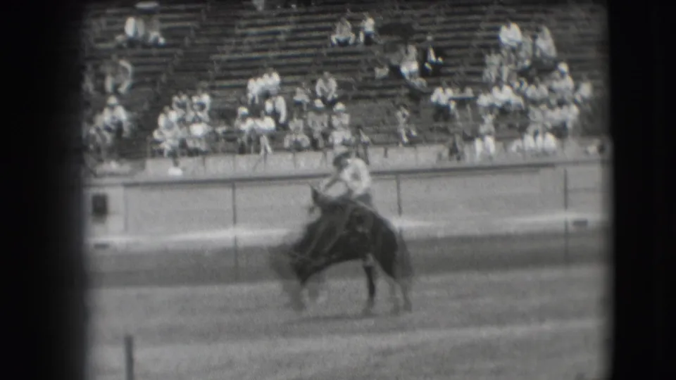 1941 Denver rodeo footage showing a cowboy on a bucking horse before a seated crowd in outdoor bleachers.