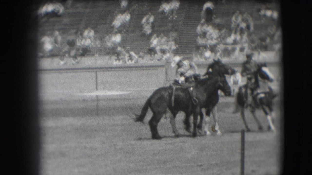 In 1941 Denver rodeo footage, several mounted cowboys appear near the arena rail while spectators watch from bleachers.