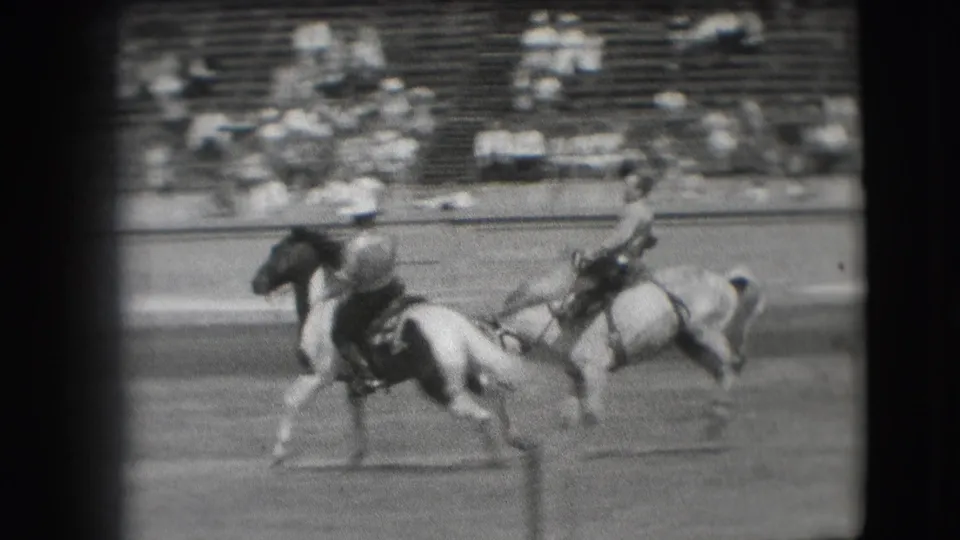 A second rider appears near the bucking horse and cowboy, suggesting arena support during the Denver rodeo sequence.