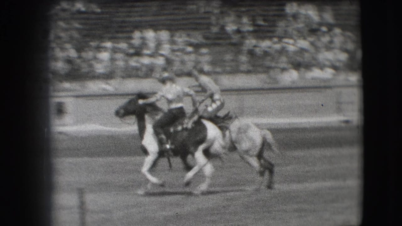 In the stated 1941 Denver rodeo setting, a cowboy leans low during a horseback trick as spectators sit in the grandstand.