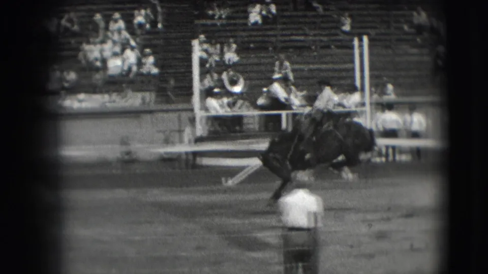 1941 Denver rodeo footage shows a rider leaning back on a bucking horse as spectators watch from wooden bleachers.