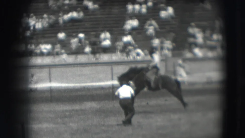 In the supplied 1941 Denver rodeo footage, a cowboy rides a bucking horse while a man stands on the arena floor and spectators watch from bleachers.