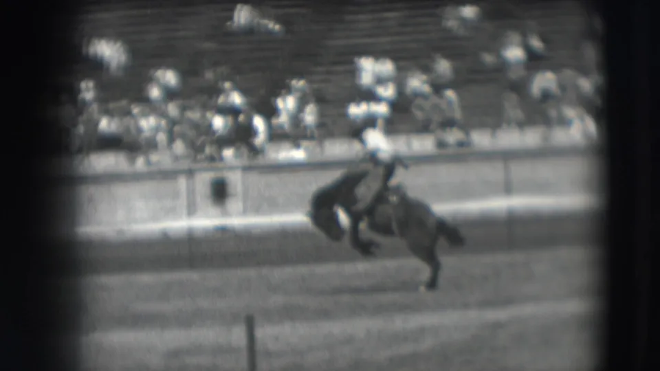 In the supplied 1941 Denver rodeo footage, a rider leans forward on a bucking horse as spectators watch from bleachers.