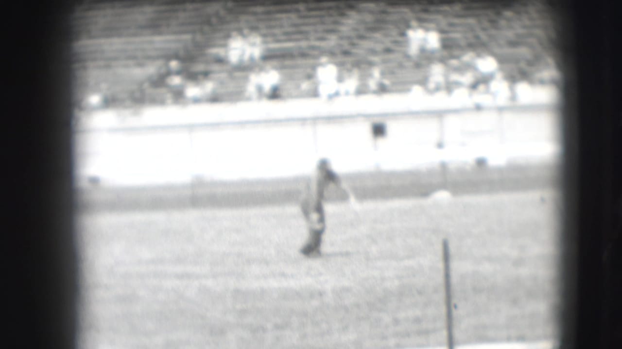 A distant arena figure appears on the field during the 1941 Denver rodeo, with seated spectators beyond the barrier.