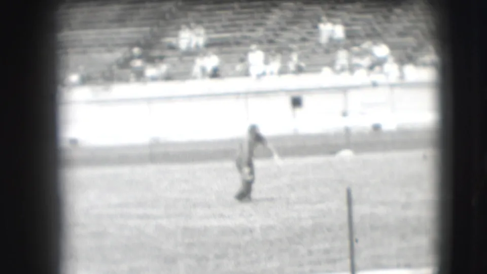 A distant arena figure appears on the field during the 1941 Denver rodeo, with seated spectators beyond the barrier.