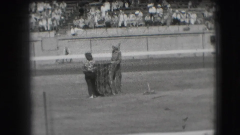 In 1941 Denver footage, two horseshoes players stand by the pit on a grassy field as a stadium audience watches from the bleachers.