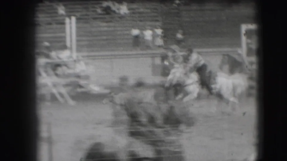 Fast-moving 1941 rodeo action shows the rider, horse, and calf in a soft, blurred frame with spectators beyond the arena.