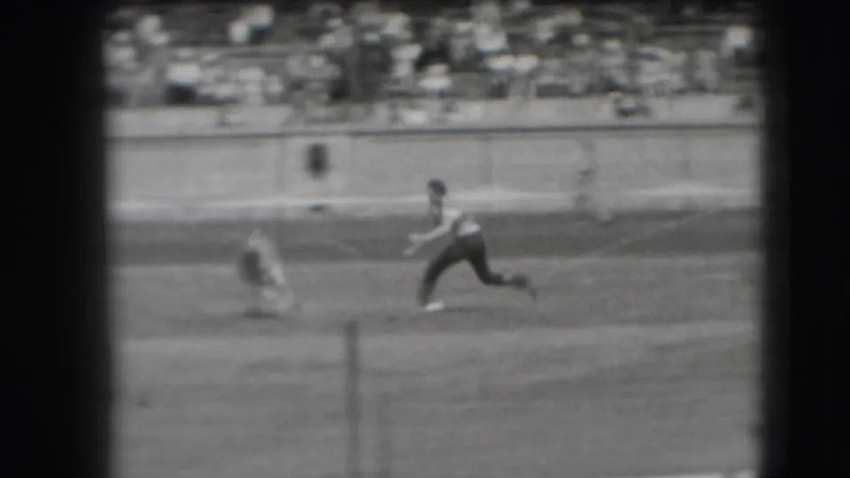 Black-and-white 8mm frame from Denver in 1941 showing a cow running ahead of a mounted cowboy during a rodeo roping run.
