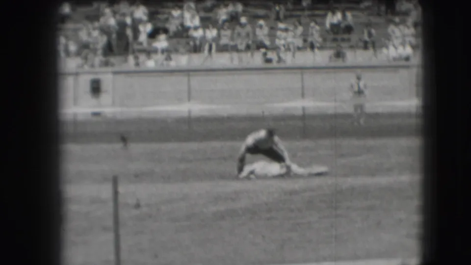 In the supplied 1941 Denver rodeo footage, a cowboy appears to wrestle a steer low to the ground as spectators watch from the far bleachers.