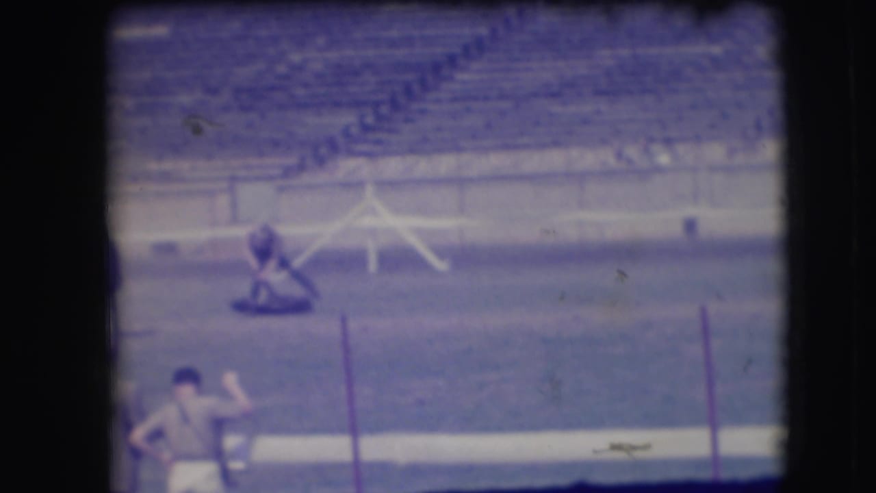 Distant rodeo arena view with a cowboy near a cow and stadium seating behind.