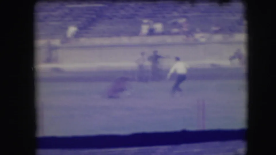 A rodeo contestant appears to run after the calf in the Denver arena, with the horse and bleacher crowd visible behind the action.