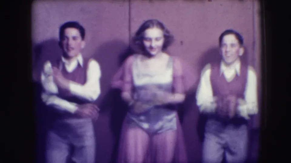 Three young performers in 1941 Joliet footage face the camera, with two boys in vests flanking a girl in a dress.