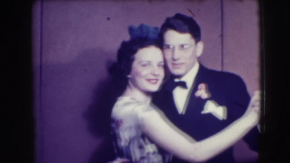 The formal couple continues a slow dance, with the woman smiling and the man looking toward the camera in 1941 Joliet footage.