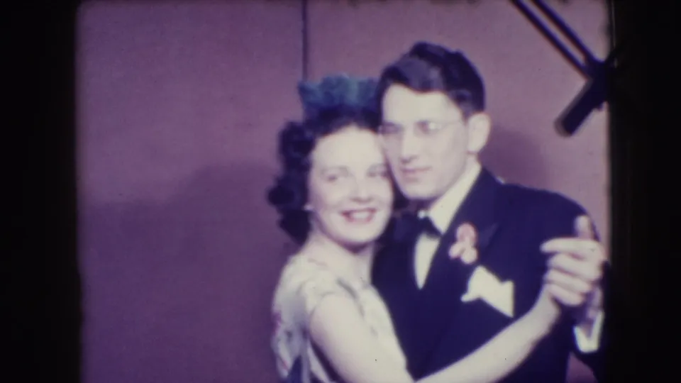 In supported 1941 Joliet home-movie footage, an adult woman in a light dress dances with a man in a dark suit and bow tie.