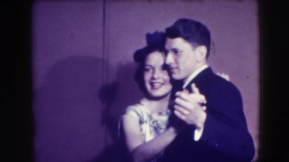 A formally dressed couple dances in the 1941 Joliet home-movie scene, with the woman smiling and the man in a dark suit.