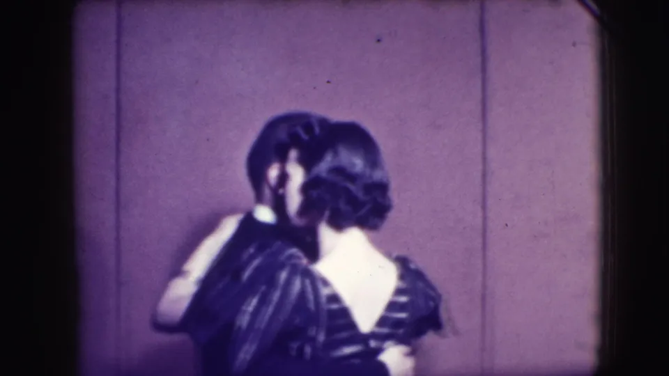 A second adult couple dances close together, seen from behind, with the woman wearing a dark striped dress in the Joliet 1941 footage.