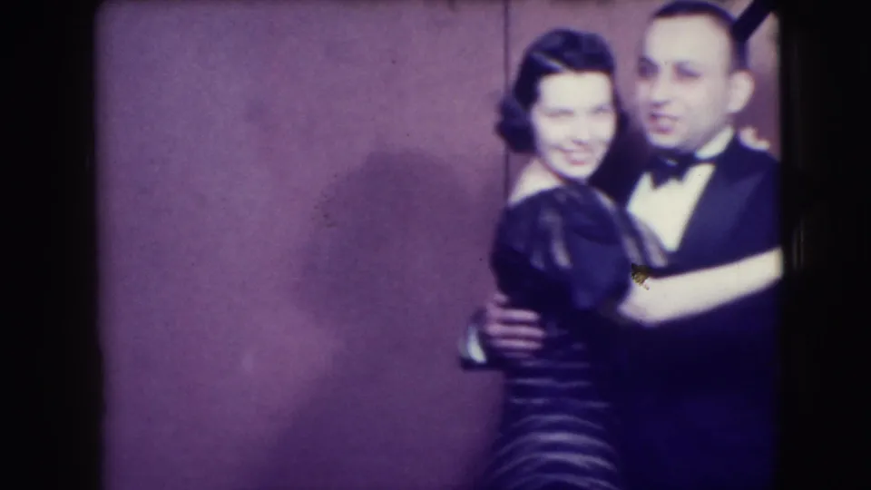A man in a tuxedo dances with a smiling woman while another dancer's back fills the foreground in the 1941 Joliet clip.