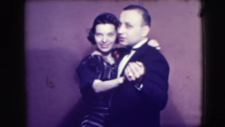 In 1941 Joliet, Illinois home-movie footage, a formally dressed adult couple dances close together against a plain purple backdrop.