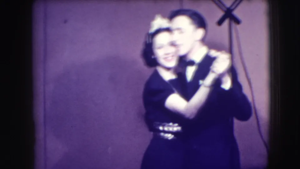 A softly blurred 1941 Joliet frame shows the formally dressed couple smiling together as they continue their dance.