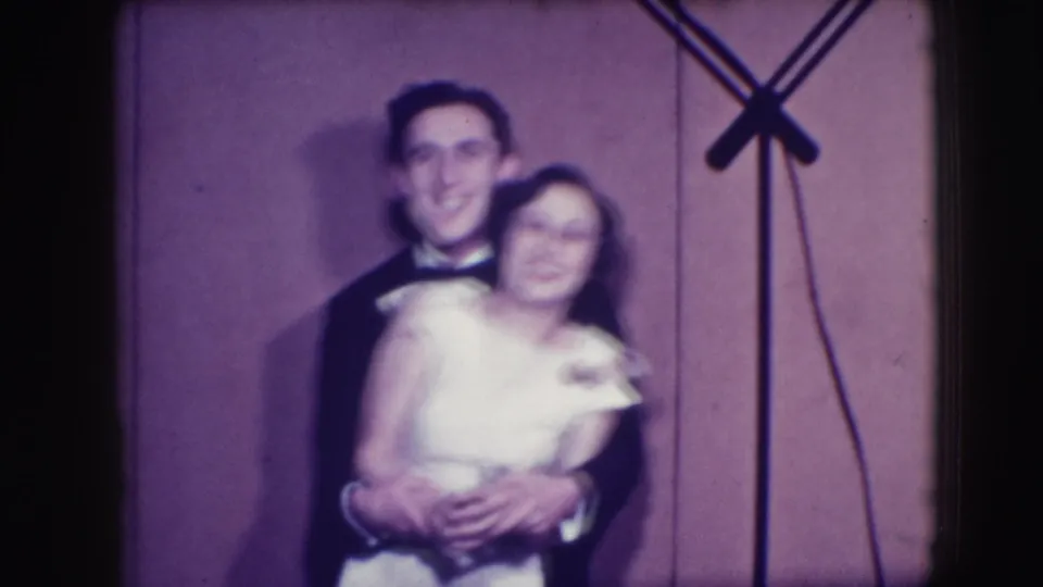 The young couple smiles in a close embrace in the 1941 Joliet 8mm footage, with the woman held from behind against a plain backdrop.