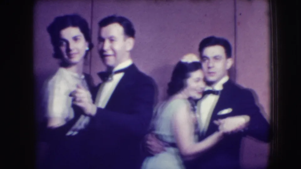 Two couples in tuxedos and light dresses smile and dance close to the camera in the 1941 Joliet formal-event footage.