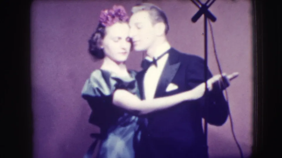 The man in a tuxedo and woman in a ruffled dress continue a close dance pose in the 1941 Joliet home-movie footage.
