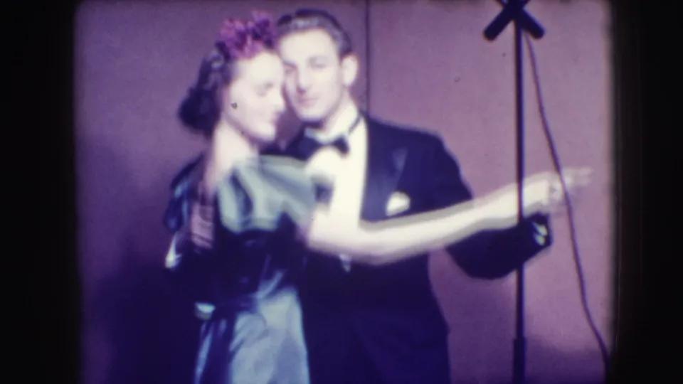 In 1941 Joliet home-movie footage, a formally dressed couple dances closely in a dim nightclub setting.
