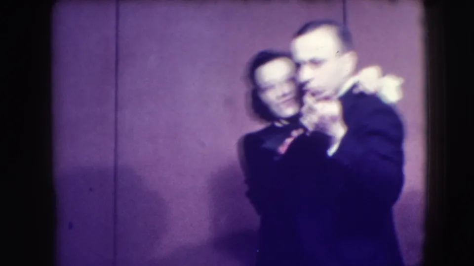 A formally dressed couple appears mid-dance in the 1941 Joliet nightclub scene, partially softened by motion and low light.