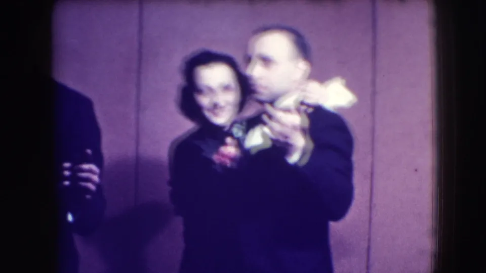 A couple in formal evening clothing dances closely in the 1941 Joliet home-movie scene, with another figure cropped at the edge.