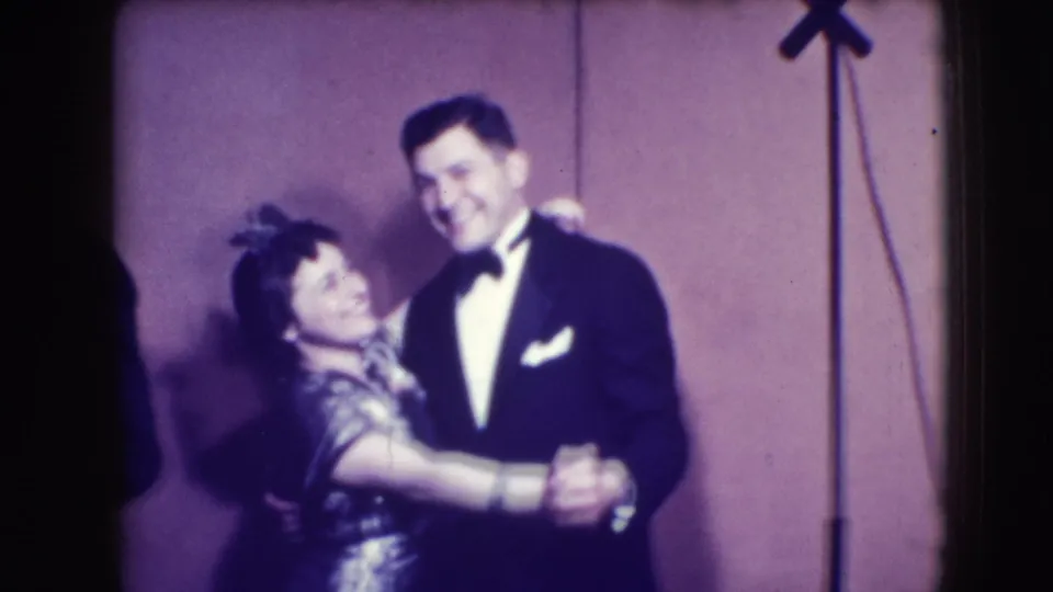 The couple remain in a close dance hold on a Joliet stage, with formal 1940s clothing and microphone stands visible.
