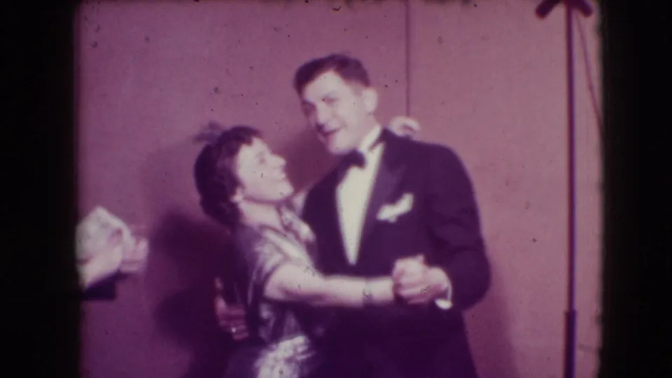 The couple continue their stage dance in Joliet, Illinois, with a microphone stand and warm color-shifted 8mm texture visible.