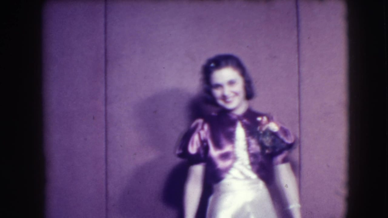 Woman in a shiny pink dress poses against a plain purple backdrop.