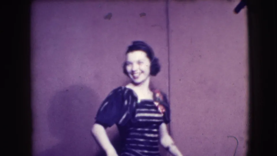 A woman in Joliet, Illinois, smiles toward the camera while wearing a dark striped dress with puffed sleeves and a flower accent.