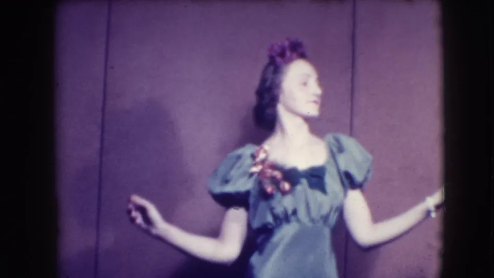 A woman in a green puffed-sleeve dress with floral trim poses in profile against a purple backdrop in Joliet, Illinois, 1941.