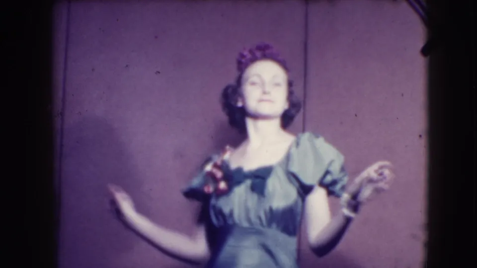 In the final frame, the woman faces forward in the green puffed-sleeve dress, raising one hand as she poses for the 8mm camera.