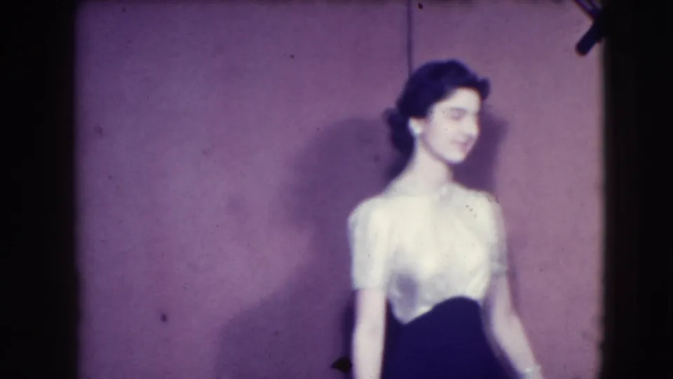 In the Joliet, Illinois 1941 clip, an adult woman in a white blouse and dark skirt turns in profile with her hair styled up.