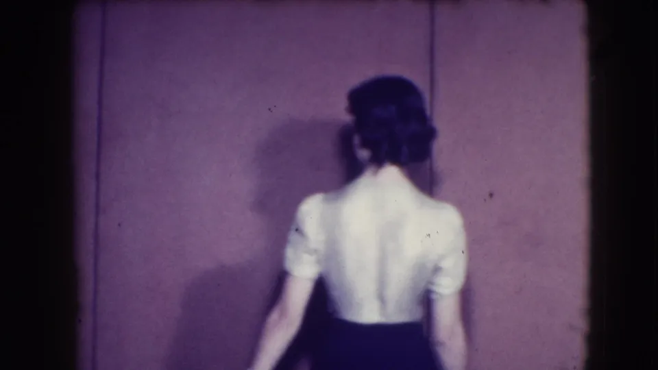 The woman in the white blouse and dark skirt is seen from behind as she turns, showing the back of the outfit in the 1941 Joliet home movie.